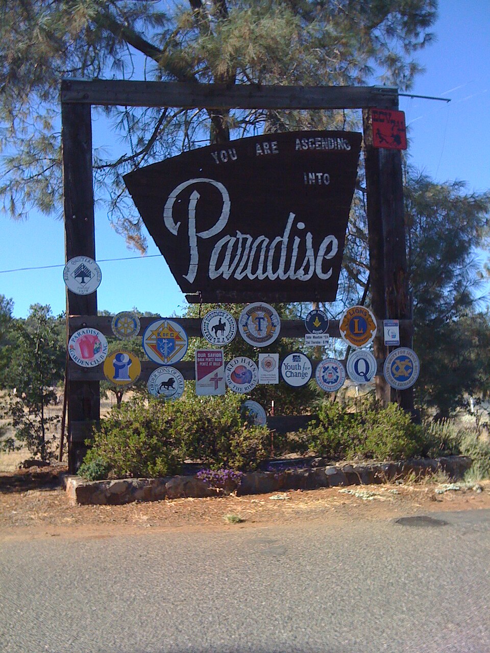 The Welcome to Paradise sign, covered in community club emblems