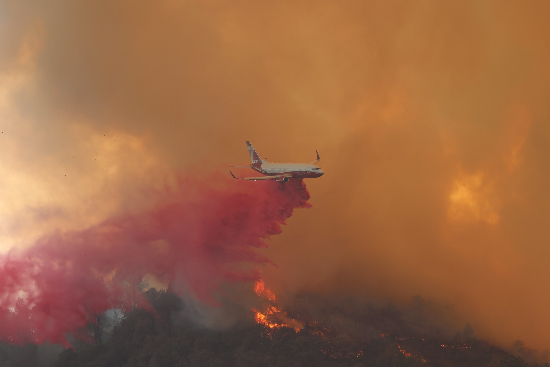 Air tanker dropping fire retardant over a burning ridge